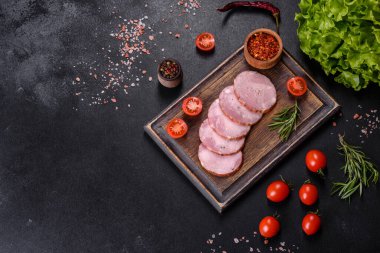 Lezzetli taze jambon. Koyu beton arka planda tahta kesme tahtasının üzerinde dilimler var.
