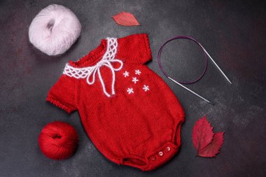 Kırmızı ipliklerden örülmüş yeni doğmuş bir bebek için kıyafet. Hobi, ev yapımı kıyafetler.