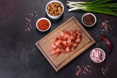 Baharatlı ve otlu kurutulmuş et dilimleri. Siyah bir arka planda bira için atıştırmalıklar. Üst görünüm