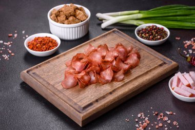 Baharatlı ve otlu kurutulmuş et dilimleri. Siyah bir arka planda bira için atıştırmalıklar. Üst görünüm