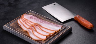 Tahta kesme tahtasındaki pastırma dilimleri. Domuz eti. Siyah arka plan. Üst görünüm