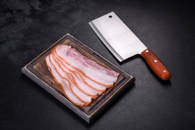 Tahta kesme tahtasındaki pastırma dilimleri. Domuz eti. Siyah arka plan. Üst görünüm