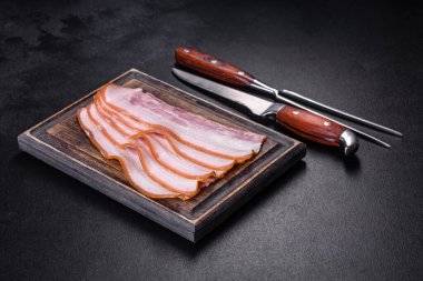 Tahta kesme tahtasındaki pastırma dilimleri. Domuz eti. Siyah arka plan. Üst görünüm