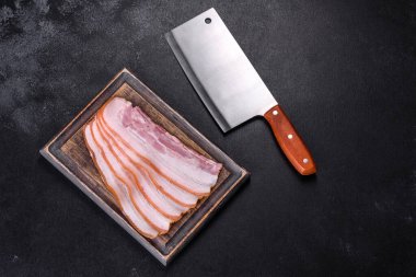 Tahta kesme tahtasındaki pastırma dilimleri. Domuz eti. Siyah arka plan. Üst görünüm