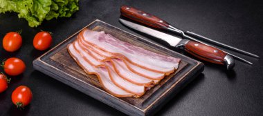 Tahta kesme tahtasındaki pastırma dilimleri. Domuz eti. Siyah arka plan. Üst görünüm