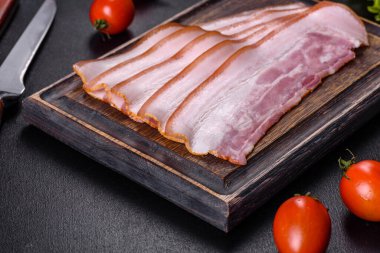 Tahta kesme tahtasındaki pastırma dilimleri. Domuz eti. Siyah arka plan. Üst görünüm