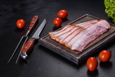 Tahta kesme tahtasındaki pastırma dilimleri. Domuz eti. Siyah arka plan. Üst görünüm