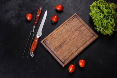 Kahverengi dikdörtgen ahşap kesme tahtası. Koyu beton arka planda tuz ve baharatlar var. Evde yemek pişirmek.