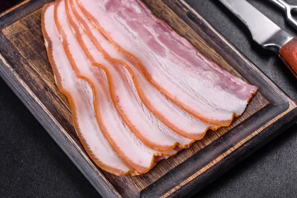 Tahta kesme tahtasındaki pastırma dilimleri. Domuz eti. Siyah arka plan. Üst görünüm