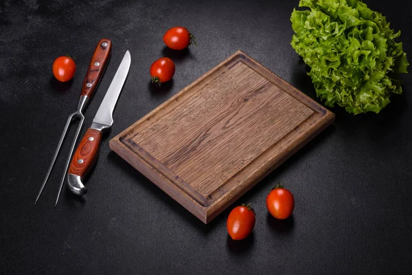 Kahverengi dikdörtgen ahşap kesme tahtası. Koyu beton arka planda tuz ve baharatlar var. Evde yemek pişirmek.