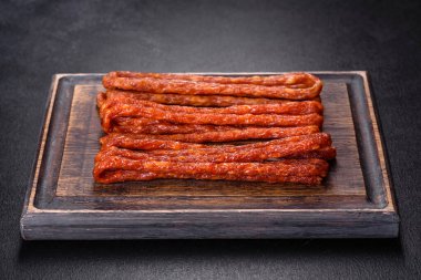 Lezzetli taze füme sıcak sosis ve koyu beton bir masada kiraz domatesleri.