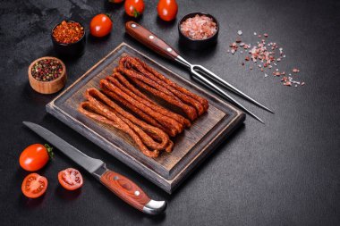 Lezzetli taze füme sıcak sosis ve koyu beton bir masada kiraz domatesleri.