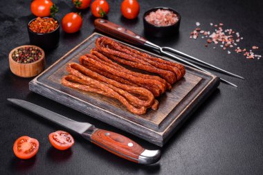 Lezzetli taze füme sıcak sosis ve koyu beton bir masada kiraz domatesleri.