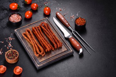 Lezzetli taze füme sıcak sosis ve koyu beton bir masada kiraz domatesleri.