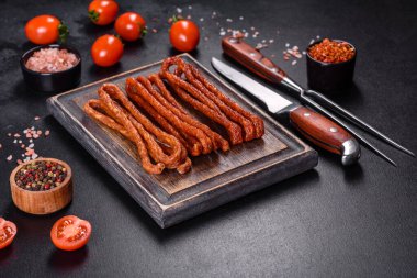 Lezzetli taze füme sıcak sosis ve koyu beton bir masada kiraz domatesleri.