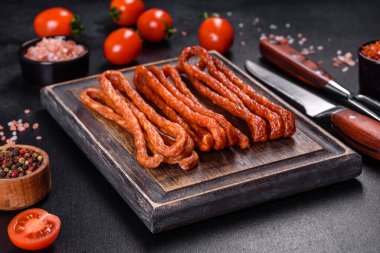 Lezzetli taze füme sıcak sosis ve koyu beton bir masada kiraz domatesleri.