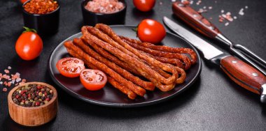 Lezzetli taze füme sıcak sosis ve koyu beton bir masada kiraz domatesleri.