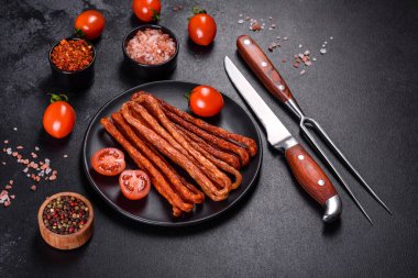 Lezzetli taze füme sıcak sosis ve koyu beton bir masada kiraz domatesleri.