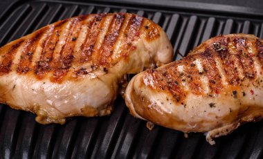 Lezzetli taze ızgara tavuk filetosu, esrarlı baharatlar ve çimento kaplı otlar. Ateşte pişirilmiş bir tabak.