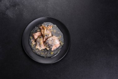 Siyah yuvarlak bir tabakta koyu beton bir arka planda yağda konserve sardalya. Lezzetli bir atıştırmalık