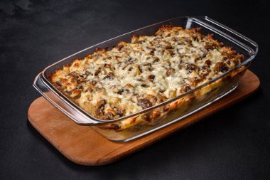 Etli, mantarlı, sebzeli ve patatesli lezzetli bir yemek. Fırında kremalı sosta pişmiş. Ev yemeği pişirmek.