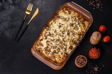 Etli, mantarlı, sebzeli ve patatesli lezzetli bir yemek. Fırında kremalı sosta pişmiş. Ev yemeği pişirmek.