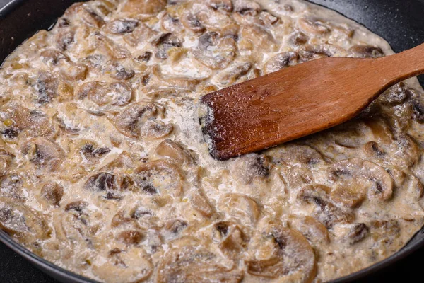 Lezzetli taze şampiyonlar, siyah bir tavada kaynatılmış kremalı sosla dilimlenmiş.