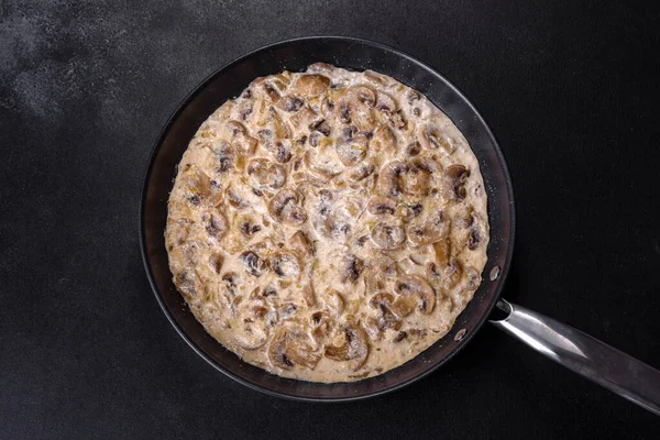 Lezzetli taze şampiyonlar, siyah bir tavada kaynatılmış kremalı sosla dilimlenmiş.