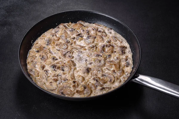 Lezzetli taze şampiyonlar, siyah bir tavada kaynatılmış kremalı sosla dilimlenmiş.