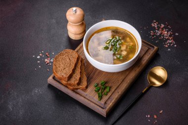 Beyaz bir kasede koyu beton bir zemine karşı lezzetli, sağlıklı bir çorba, domates, patates, baharat ve otlar. Vejetaryen yemeği.