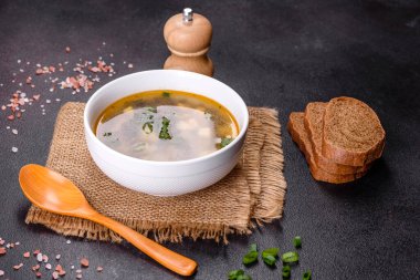 Beyaz bir kasede koyu beton bir zemine karşı lezzetli, sağlıklı bir çorba, domates, patates, baharat ve otlar. Vejetaryen yemeği.