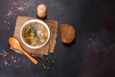 Beyaz bir kasede koyu beton bir zemine karşı lezzetli, sağlıklı bir çorba, domates, patates, baharat ve otlar. Vejetaryen yemeği.