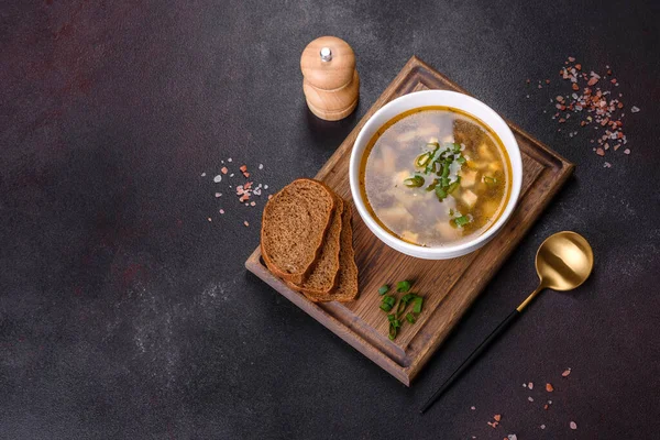 Beyaz bir kasede koyu beton bir zemine karşı lezzetli, sağlıklı bir çorba, domates, patates, baharat ve otlar. Vejetaryen yemeği.