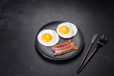 Yağda yumurta, pastırma, fasulye, domates, baharat ve bitkilerle İngiliz kahvaltısı. Güne doyurucu ve doyurucu bir başlangıç.