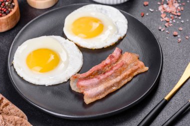 Yağda yumurta, pastırma, fasulye, domates, baharat ve bitkilerle İngiliz kahvaltısı. Güne doyurucu ve doyurucu bir başlangıç.