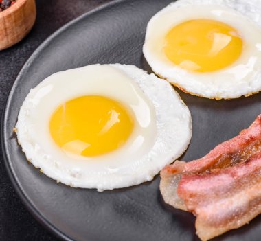 Yağda yumurta, pastırma, fasulye, domates, baharat ve bitkilerle İngiliz kahvaltısı. Güne doyurucu ve doyurucu bir başlangıç.