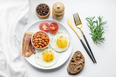 Yağda yumurta, pastırma, fasulye, domates, baharat ve bitkilerle İngiliz kahvaltısı. Güne doyurucu ve doyurucu bir başlangıç.