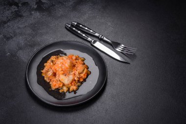 Siyah arka planda domatesli haşlanmış beyaz balık.