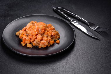 Siyah arka planda domatesli haşlanmış beyaz balık.