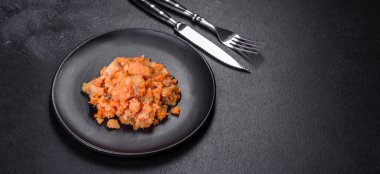 Siyah arka planda domatesli haşlanmış beyaz balık.