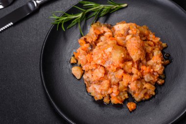 Siyah arka planda domatesli haşlanmış beyaz balık.