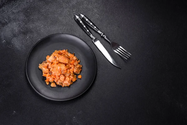 Siyah arka planda domatesli haşlanmış beyaz balık.