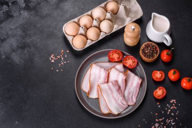 Gri bir tabakta koyu beton arka planda dilimlenmiş leziz taze pastırma. Lezzetli besleyici bir kahvaltı hazırlıyorum.