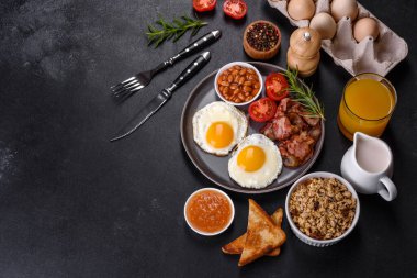 Yağda yumurta, pastırma, fasulye, bir bardak meyve suyu, yulaf kurabiyesi, süt ve reçelli lezzetli ve sağlıklı bir kahvaltı. Günün başında sağlıklı beslenmek.