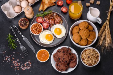 Yağda yumurta, pastırma, fasulye, bir bardak meyve suyu, yulaf kurabiyesi, süt ve reçelli lezzetli ve sağlıklı bir kahvaltı. Günün başında sağlıklı beslenmek.