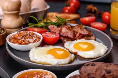 Yağda yumurta, pastırma, fasulye, bir bardak meyve suyu, yulaf kurabiyesi, süt ve reçelli lezzetli ve sağlıklı bir kahvaltı. Günün başında sağlıklı beslenmek.