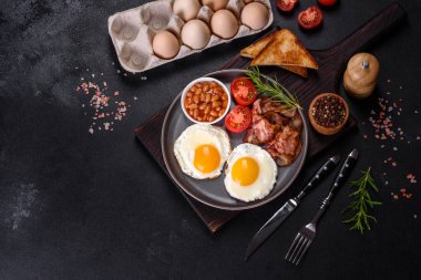 Yağda yumurta, pastırma, fasulye, bir bardak meyve suyu, yulaf kurabiyesi, süt ve reçelli lezzetli ve sağlıklı bir kahvaltı. Günün başında sağlıklı beslenmek.
