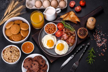 Yağda yumurta, pastırma, fasulye, bir bardak meyve suyu, yulaf kurabiyesi, süt ve reçelli lezzetli ve sağlıklı bir kahvaltı. Günün başında sağlıklı beslenmek.