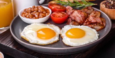 Yağda yumurta, pastırma, fasulye, bir bardak meyve suyu, yulaf kurabiyesi, süt ve reçelli lezzetli ve sağlıklı bir kahvaltı. Günün başında sağlıklı beslenmek.