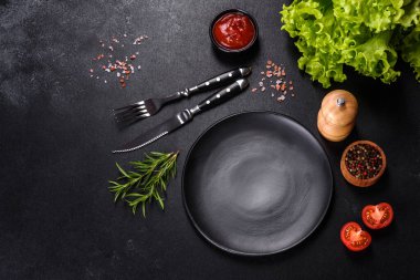 Empty gray plate on a dark background with a knife and fork